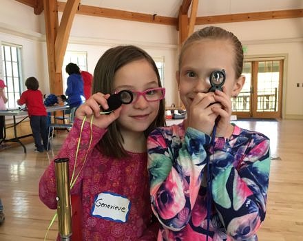 Two elementary school students peer through hand lenses. (photo © Margaret Baker)