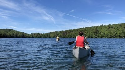 Four people -- in two canoes -- paddle across Lake Nubanusit, on their way to Spoonwood Pond. (photo © Brett Amy Thelen)