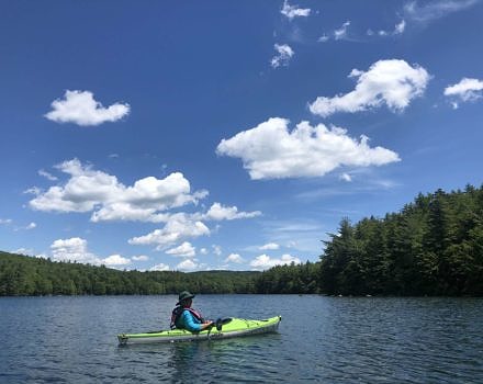 A person in a green kayak on Lake Nubanusit. (photo © Brett Amy Thelen)
