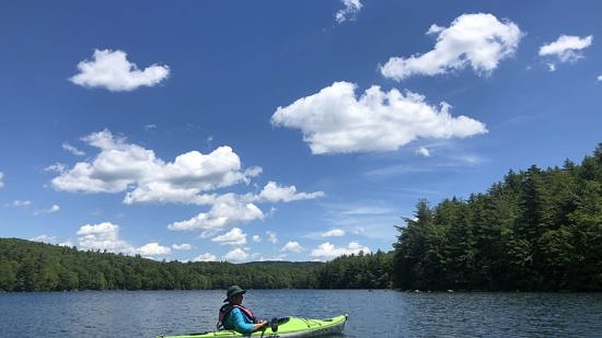 A person in a green kayak on Lake Nubanusit. (photo © Brett Amy Thelen)