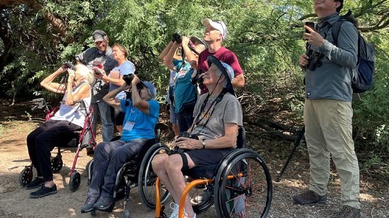 A group of people, some in wheelchairs, holding binoculars. (photo © Freya McGregor)