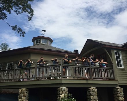A groupd of kids peer through binoculars on the Harris Center front deck.