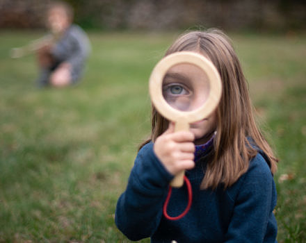 A girl uses a magnifying glass to look closely at an animal skull. (photo © Ben Conant)