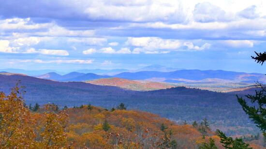 Colorful mountain ridges that expand into the far distance, with a sky of clouds. (photo © Alan D Perkins)