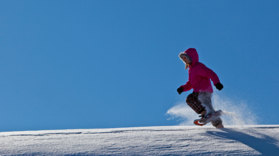 Girls runs through snow in snowshoes. (photo © Canva Commons)