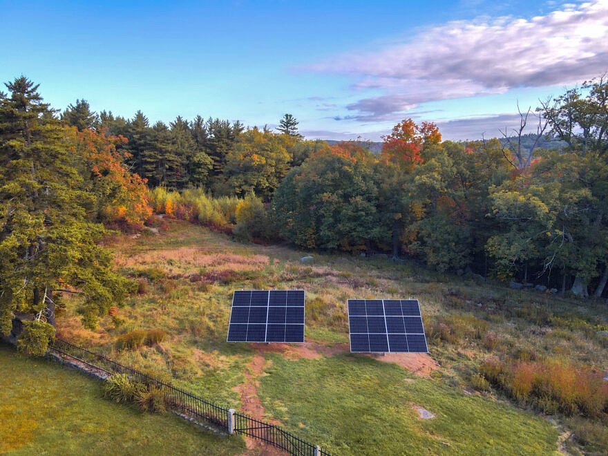 Two solar panels in a field by the Harris Center with a mountain in the distance (Photo © James Newsom)