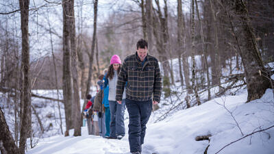 Jeremy Wilson and Susie Spikol lead a group through snowy woods (photo © Ben Conant)