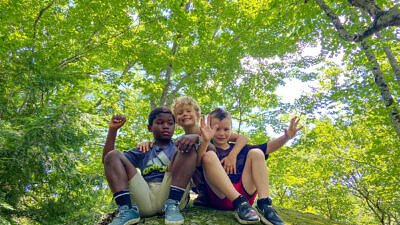 Boys smiling from top of rock at summer camp