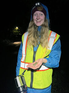 Intern Chloe March smiles while holding a gray tree frog on a spring amphibian migration night. (photo: Brett Amy Thelen)