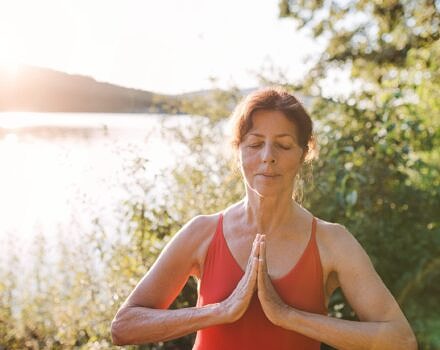 Woman in a bathing suit doing yoga by a lake (photo © Adobe)