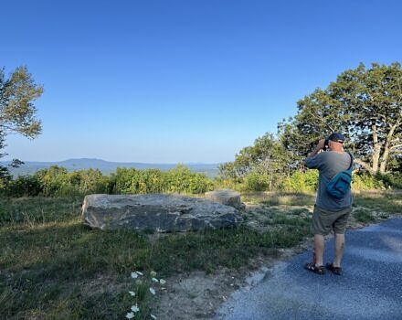 A man looks through binoculars while standing on the Beech Hill all-persons' trail. (photo © Brett Amy Thelen)