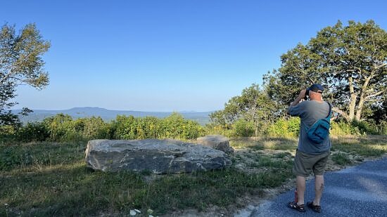 A man looks through binoculars while standing on the Beech Hill all-persons' trail. (photo © Brett Amy Thelen)