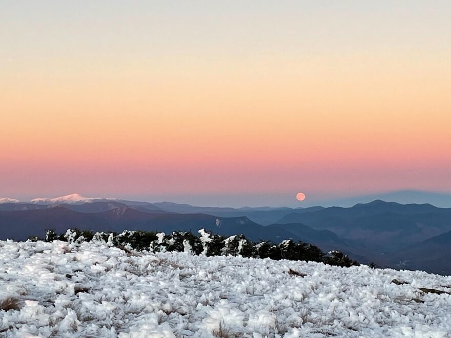 The full moon rises into the Belt of Venus. The Presidential peaks are on the left, and the shadow of Mount Moosilauke on the earth’s atmosphere can be seen on the right. (photo © Jessaka Nichols)