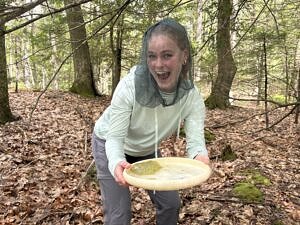 Intern Maya Carey smiles while holding a frisbee containing spotted salamander eggs. (photo © Brett Amy Thelen)