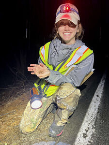Intern Grace Todd-Rogers smiles while holding a wood frog at the side of North Lincoln Street in Keene. (photo © Brett Amy Thelen)